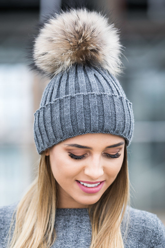 Czapka wełniana z mankietem w kolorze ciemno szarym z pomponem z naturalnego futra jenota .