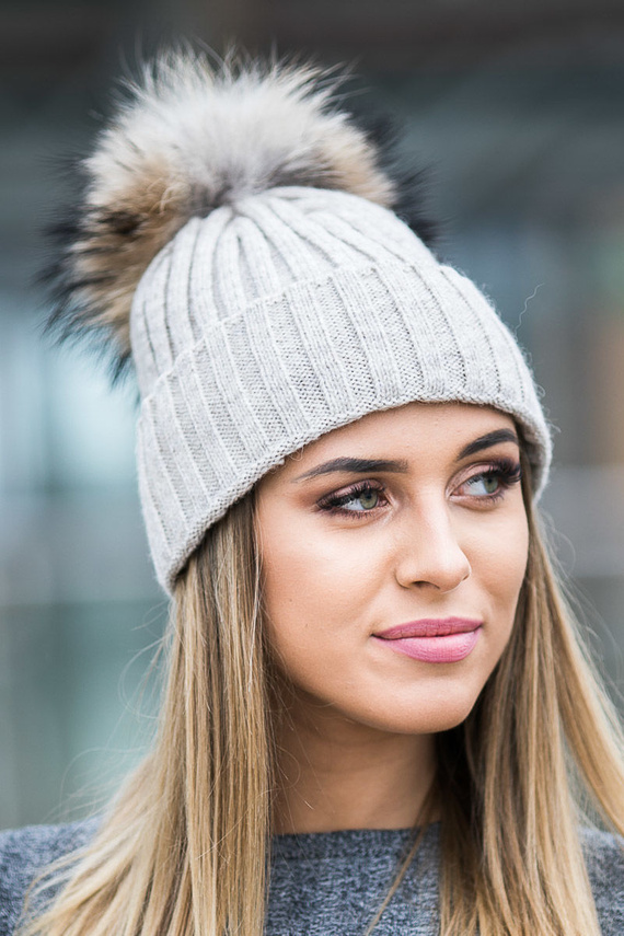 Czapka wełniana z mankietem w kolorze ecru z pomponem z naturalnego futra jenota .